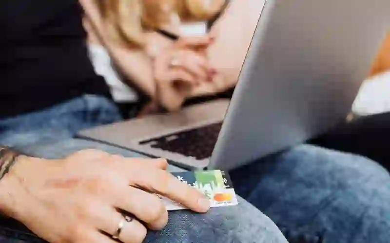 couple looking at laptop, holding a credit card.